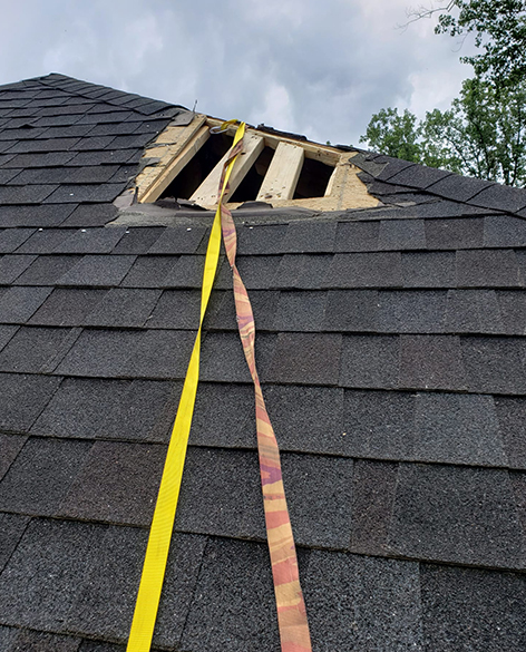 Home with roof with storm damage and a big hole